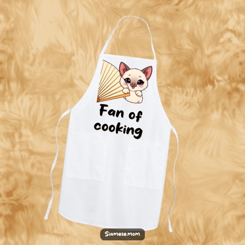 Funny happy Siamese cat peeking from behind a large, cheerful fan, featured on a cute kitchen apron.