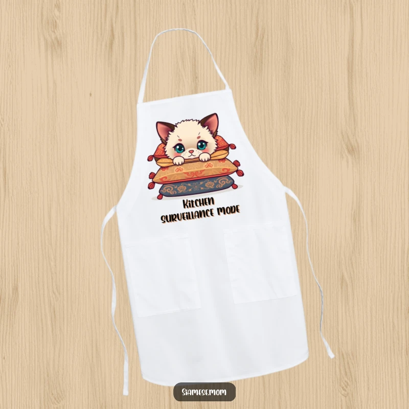 Funny Siamese cub peeking from behind cushions, a cute kitten wearing a chef hat on a humorous kitchen apron.
