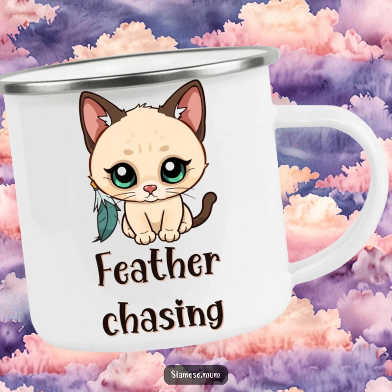 Funny Kawaii Siamese cat camping mug, wide-eyed and curious, batting at a dangling feather, ready for outdoor adventures and laughter.