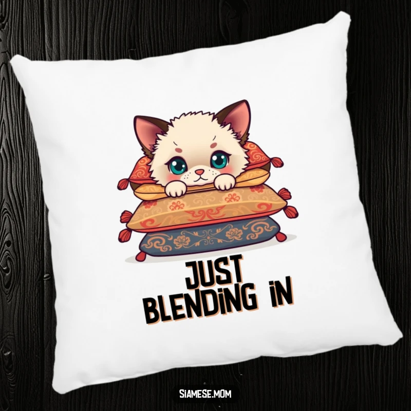 Funny Siamese cub peeking from behind cushions, a fluffy kitten offering cuddles and humor on a soft, decorative pillow.