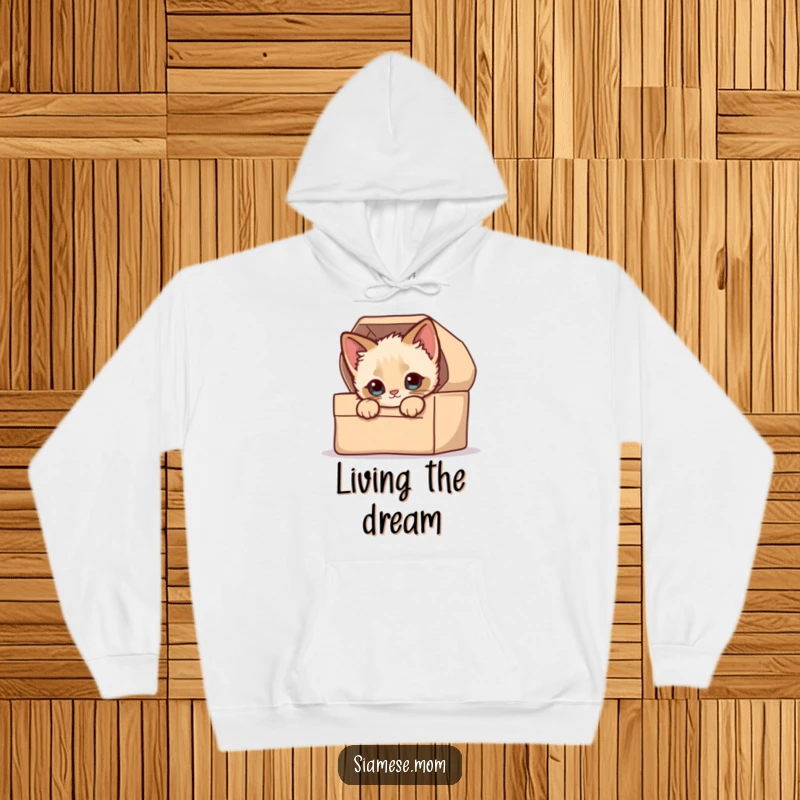 Funny Hoodie: A kawaii Siamese kitten with bright eyes peeking mischievously from a comfortable, closed cardboard box.
