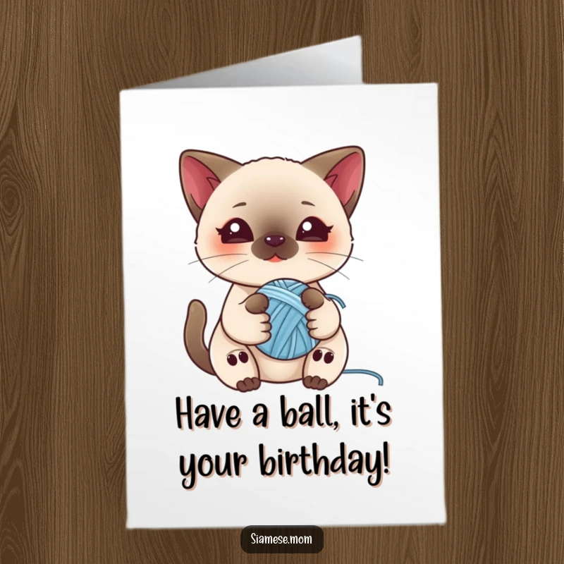 Adorable free printable birthday card with a kawaii Siamese cat playfully holding a small ball of yarn, looking cute and curious.