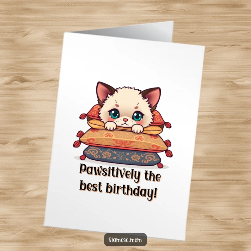 Funny Free Printable Siamese cub card, peeking playfully from behind lush cushions, perfect for birthdays.