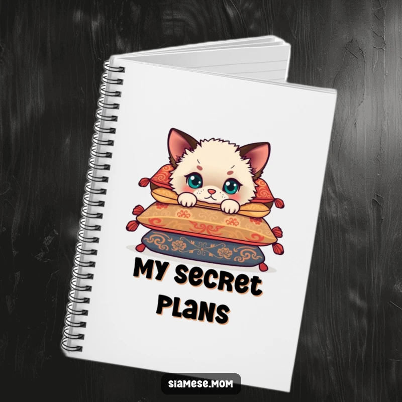 Funny Siamese cub peeking from behind cushions, a cute kitten on a notebook cover, perfect for capturing funny thoughts.